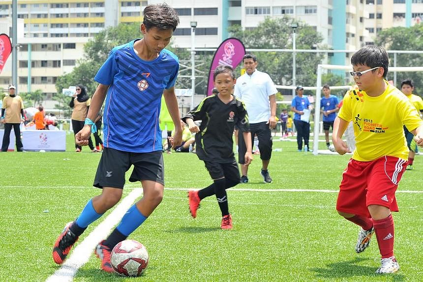 Md Erfan Bin Erhan, (blue top) 14, and Rodney Tan, (yellow top) 12, during a match at the PAssion Children's Football Family Fiesta 2015 at the Home United Youth Football Academy on Feb 8, 2015.&nbsp;-- ST PHOTO:&nbsp;LIM YAOHUI FOR THE STRAITS TIMES