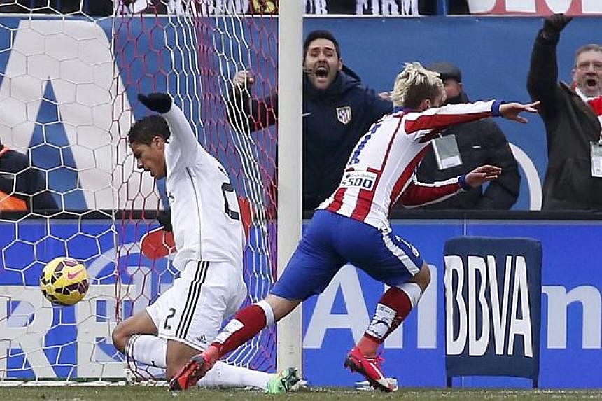 Atletico Madrid's Antoine Griezmann (right) celebrates after scoring a goal against Real Madrid during their Spanish first division soccer match in Madrid, Feb 7, 2015. -- PHOTO: REUTERS