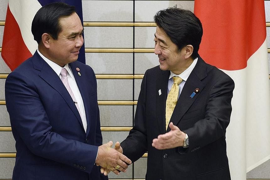 Thai Prime Minister Prayut Chan-o-cha (left) and Japanese Prime Minister Shinzo Abe shake hands prior to their meeting at Mr Abe's official residence in Tokyo, Japan on Feb 9, 2015.&nbsp;Mr Abe urged Thailand's military rulers to return as soon as po