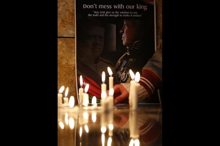 Jordan's King Abdullah being briefed last week by Joint Chiefs of Staff chairman Mashal Mohammad Al Zabin on the air strikes carried out against ISIS. (Below) A poster of the King at a candle-lit vigil held for Jordanian pilot Muath al-Kasaesbeh, who