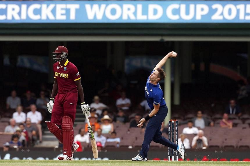 Chris Woakes (right) of England bowls next to Lendl Simmons of the West Indies during their warm-up match at the Sydney Cricket Ground on Feb 9, 2015.&nbsp;Chris Woakes took five for 19 as England claimed a comfortable nine-wicket victory in their fi