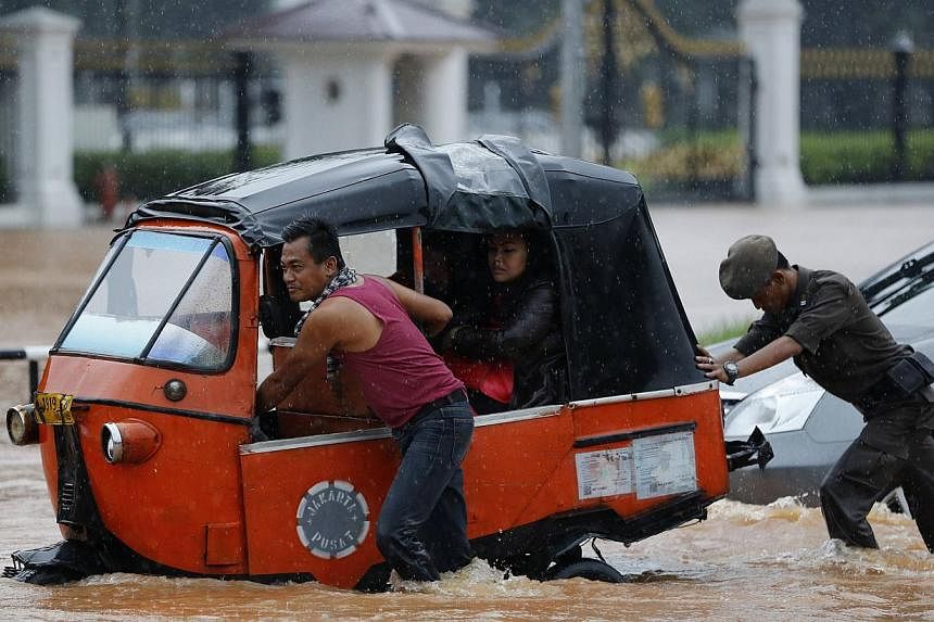 A driver pushing his Baja vehicle through flood waters outside the Presidential Palace, after heavy seasonal rains flooded parts of Jakarta on Feb 9, 2015. -- PHOTO: REUTERS