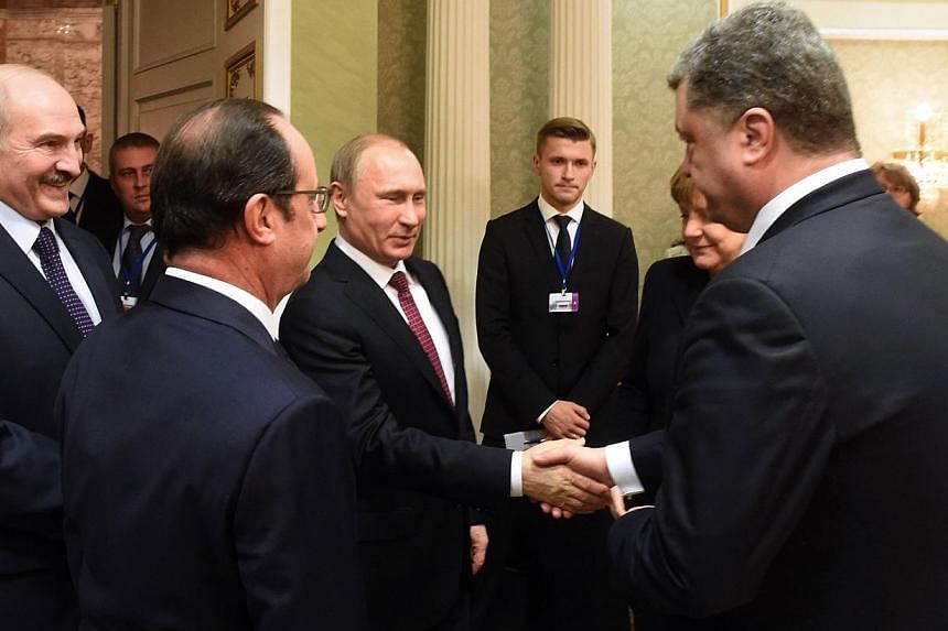 Russian President Vladimir Putin (centre) shakes hands with Ukrainian President Petro Poroshenko (right) during a meeting on February 11, 2015, in Minsk, aimed at halting a 10-month war in Ukraine where dozens were killed in the latest fighting. Russ