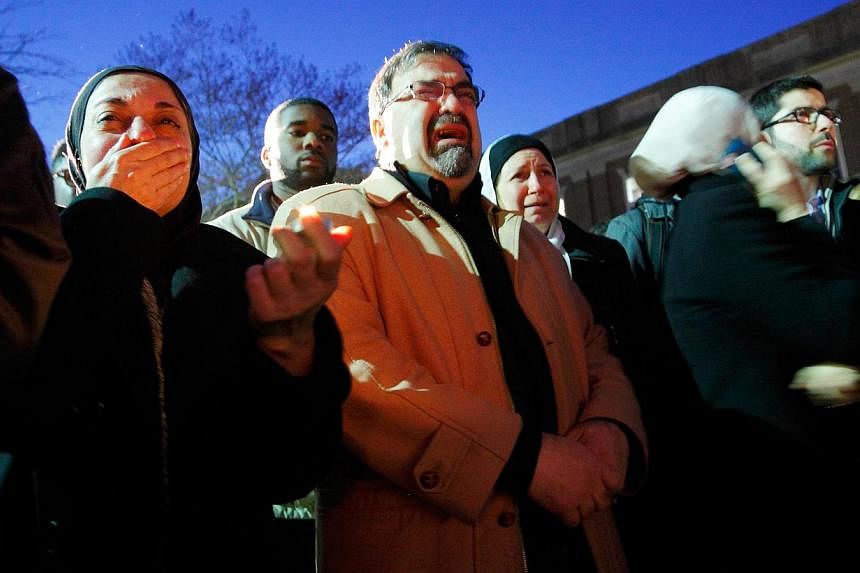 Namee Barakat (centre) and his wife Layla Barakat (centre, rear), parents of shooting victim Deah Shaddy Barakat, during a vigil in Chapel Hill. -- PHOTO: JONATHAN DRAKE FOR THE STRAITS TIMES