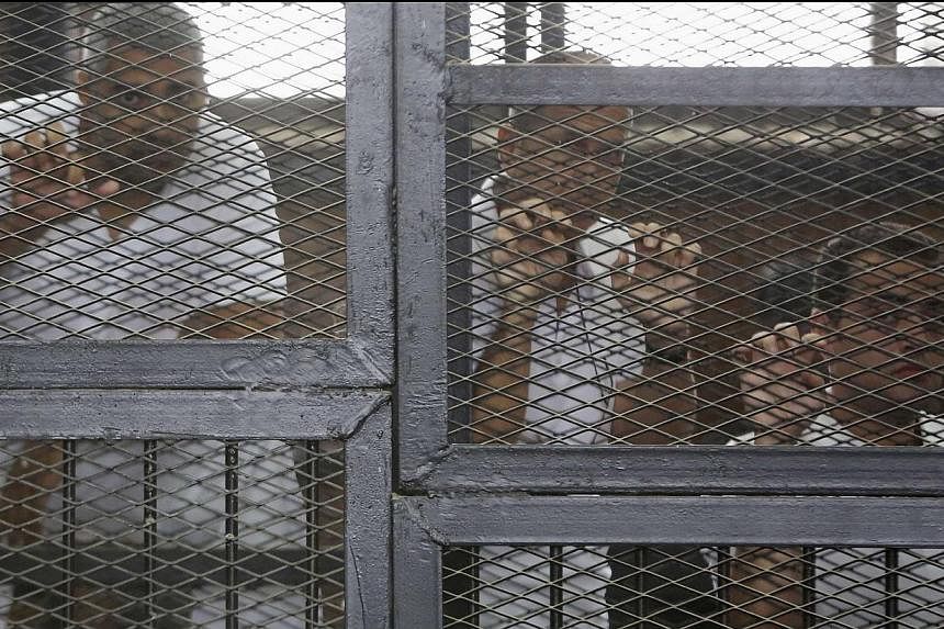 Al-Jazeera journalists (from left) Mohamed Fahmy, Peter Greste and Baher Mohamed standing behind bars at a court in Cairo in this May 15, 2014 photo. -- PHOTO: REUTERS &nbsp;