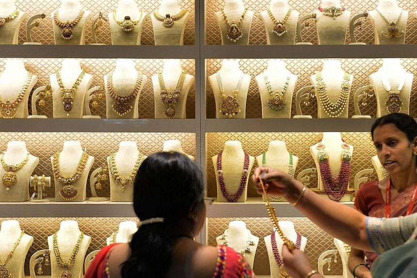 Indian residents examine gold jewellery at a stall during the 'Asia Wedding Fair 2015' in Bangalore on Feb 6, 2015. Gold demand fell for a third year on a slump in purchases from China, costing the country its place as the world's biggest buyer to In