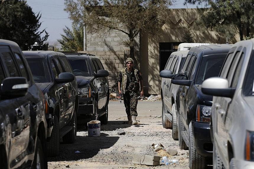 A police trooper walks past armoured US embassy cars, seized by Houthi rebels, at Sanaa airport Feb 12, 2015. -- PHOTO: REUTERS