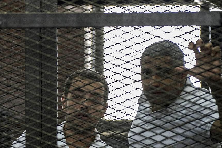 A file picture taken on Jun 23, 2014 shows Al-Jazeera news channel's journalists Egyptian-Canadian Mohamed Fahmy (right) and Egyptian Baher Mohamed (left) listening to the verdict inside the defendants cage during their trial for allegedly supporting