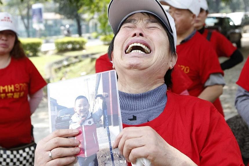 The mother of a passenger of missing Malaysia Airlines Flight MH370 holding a picture of her grandson outside the Malaysia Airlines headquarters in Kuala Lumpur on Feb 12, 2015. -- PHOTO: REUTERS