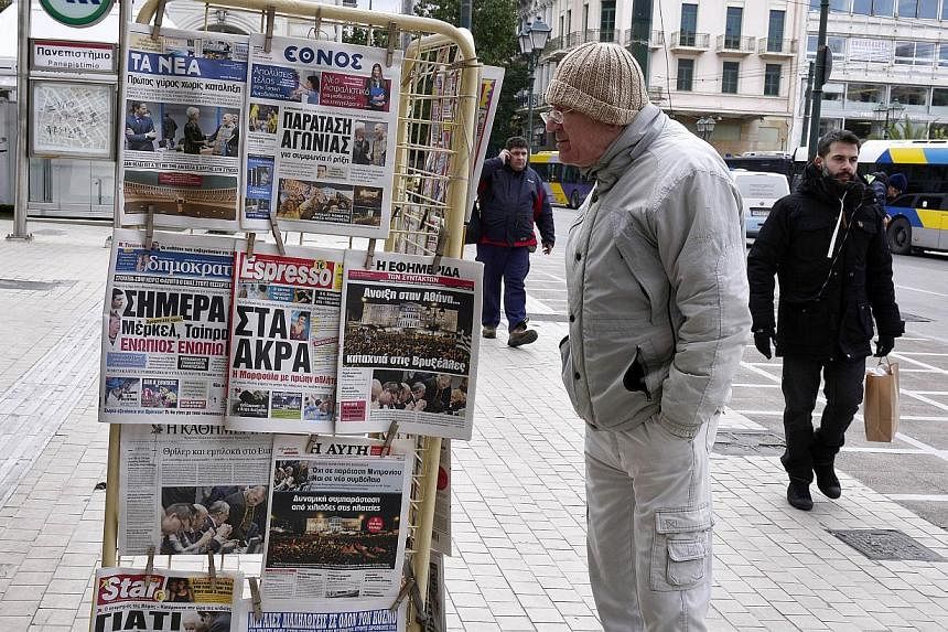 A man reds newspaper's headlines at a news stand in Athens on Feb 12, 2015&nbsp;The European Central Bank has increased the volume of emergency liquidity available to Greek banks by €5 billion (S$7.7 billion) , two newspapers reported on Thursday. 