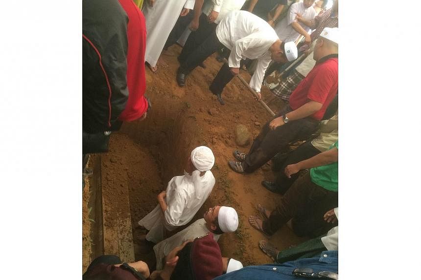 Nik Aziz's body being laid to rest as VIPs take turns to shovel earth into the grave. -- ST PHOTO: SHANNON TEOH