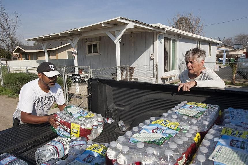 Donna Johnson (right) distributing drinking water to neighbours in East Porterville, California, on Feb 11, 2015, as water wells supplying hundreds of residents there remain dry in the fourth year of worsening drought. &nbsp;-- PHOTO: AFP