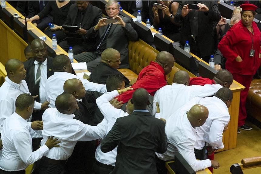 Members of the Economic Freedom Fighters, wearing red uniforms, clash with security forces during South African President's State of the Nation address in Cape Town on Feb 12, 2015.&nbsp;South Africa was Friday evaluating its hard-won democracy, embo