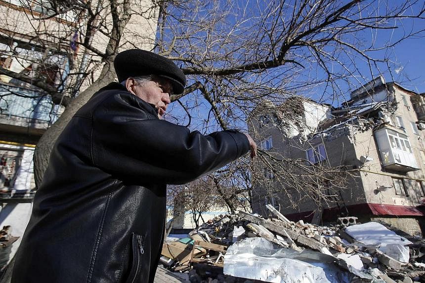A local resident points at a house damaged by a shelling in the town of Dokuchayevsk, south of Donetsk, Feb 12, 2015. -- PHOTO: REUTERS