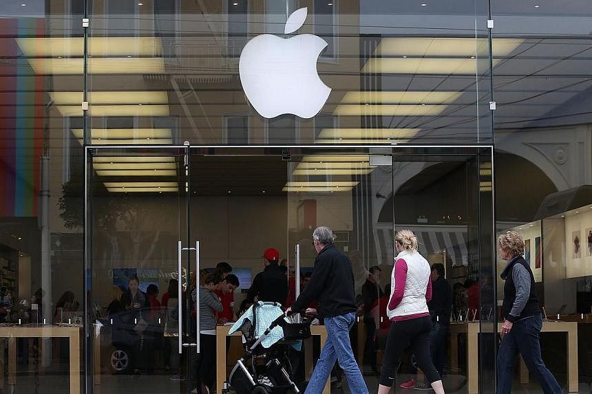 Customers entering an Apple Store on Jan 27, 2015, in San Francisco, California. The tech giant is reportedly learning how to make a self-driving electric car. -- PHOTO: AFP