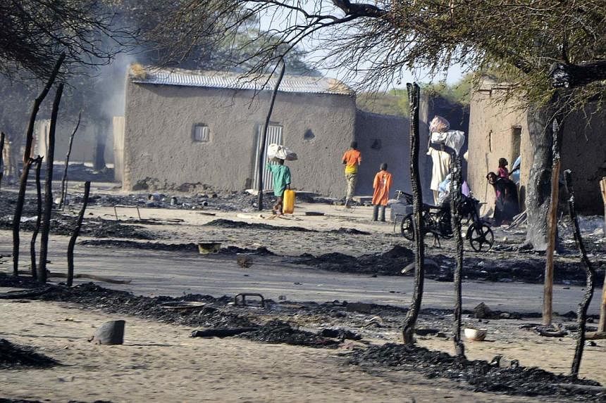 People walk in a burnt compound after an attack by Boko Haram militants in the village of Ngouboua on&nbsp;Feb 13, 2015. The group then attacked the northeastern Nigerian city of Gombe on Saturday. -- PHOTO: REUTERS