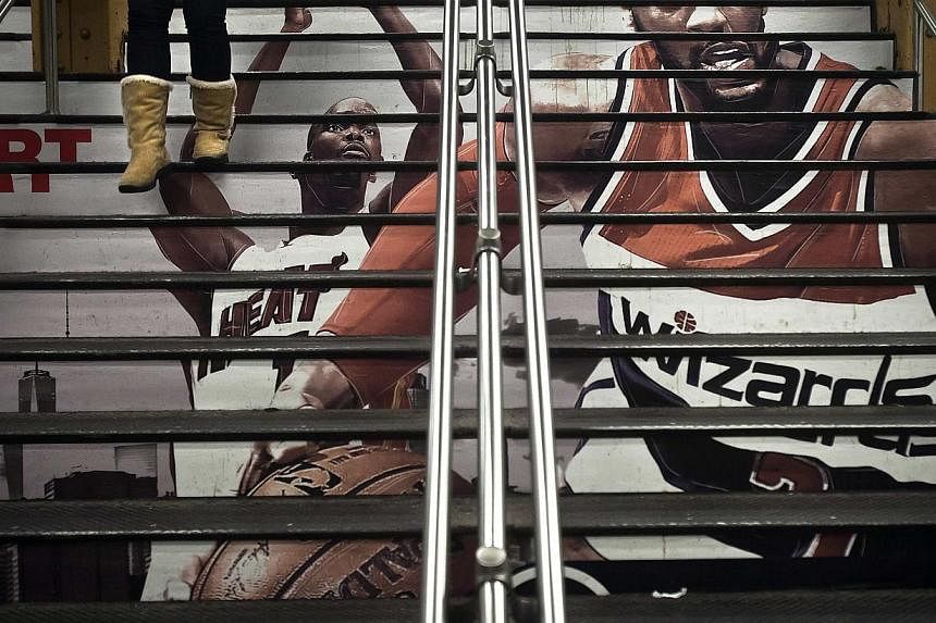 A woman walks down a flight of stairs with an advertisement for the upcoming NBA All-Star Game, in Grand Central Terminal in the Manhattan borough of New York on Feb 2, 2015. -- PHOTO: REUTERS