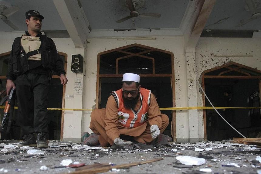 A rescue worker collecting evidence from the site of the explosion in a Shi'ite mosque in Peshawar on&nbsp;Feb 13, 2015. The death toll of the militant attack rose to 21 after an injured person died of his wounds, officials said on Saturday, Feb 14, 