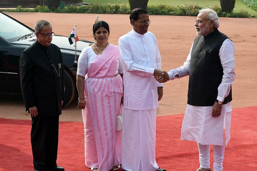 Sri Lankan President Maithripala Sirisena (second right) shakes hands with Indian Prime Minister Narendra Modi (right) as Indian President Pranab Mukherjee (left) and First Lady of Sri Lanka Jayanthi Pushpakumari (second left) look on at the Presiden