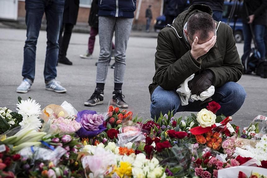 A man reacts next to flowers for the shooting victims outside the "Kruttoende" cultural centre in Copenhagen, Denmark on Feb 15, 2015.&nbsp;Danish police said on Monday they had charged two people who they detained a day earlier with aiding the man s
