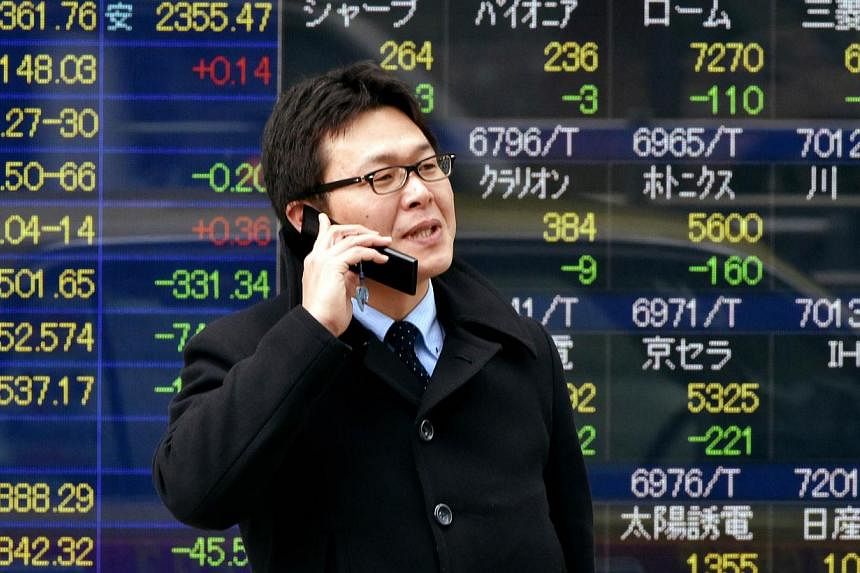 A man talks on a flip-style mobile phone in front of a share prices board in Tokyo on Jan 6, 2015.&nbsp;Japanese shipments of traditional flip-phones rose in 2014 for the first time in seven years while smartphone shipments fell, highlighting Japanes