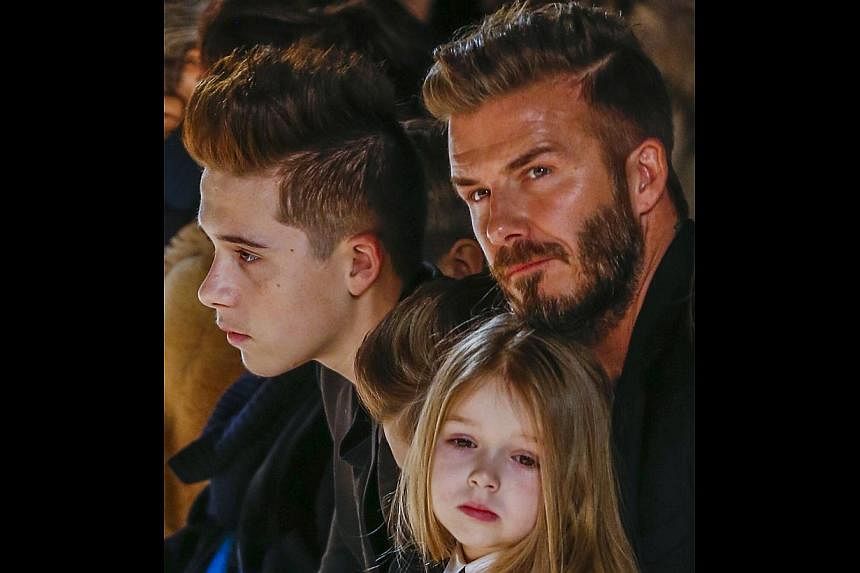 Former England captian David Beckham sits with his son, Brooklyn (left) and his daughter, Harper, during a presentation of the Victoria Beckham Fall/Winter 2015 collection during New York Fashion Week on Sunday. -- PHOTO: REUTERS