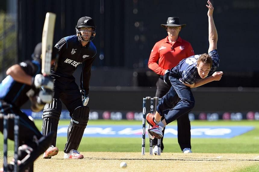 Scotland bowler Josh Davey (right) sends down a delivery to New Zealand batsman Adam Milne (left) as fellow batsman Daniel Vettori (second left) looks on during their 2015 Cricket World Cup match in Dunedin on Feb 17, 2015.&nbsp;New Zealand limped to
