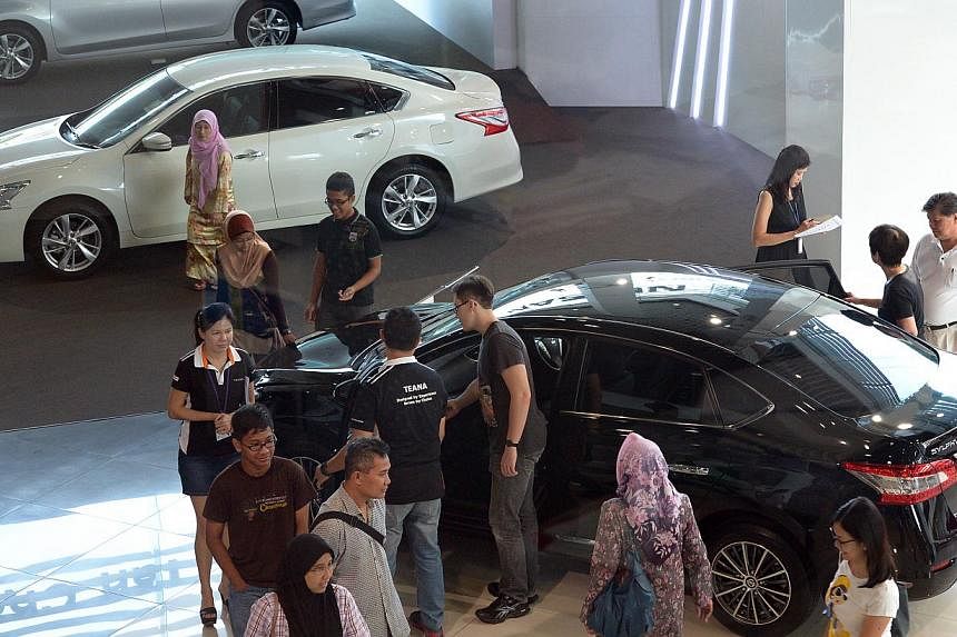 Potential buyers at the Nissan showroom in Ubi Road on May 10, 2014. Certificates of entitlement (COE) premiums ended mostly lower in the latest tender on Tuesday. -- PHOTO: ST FILE
