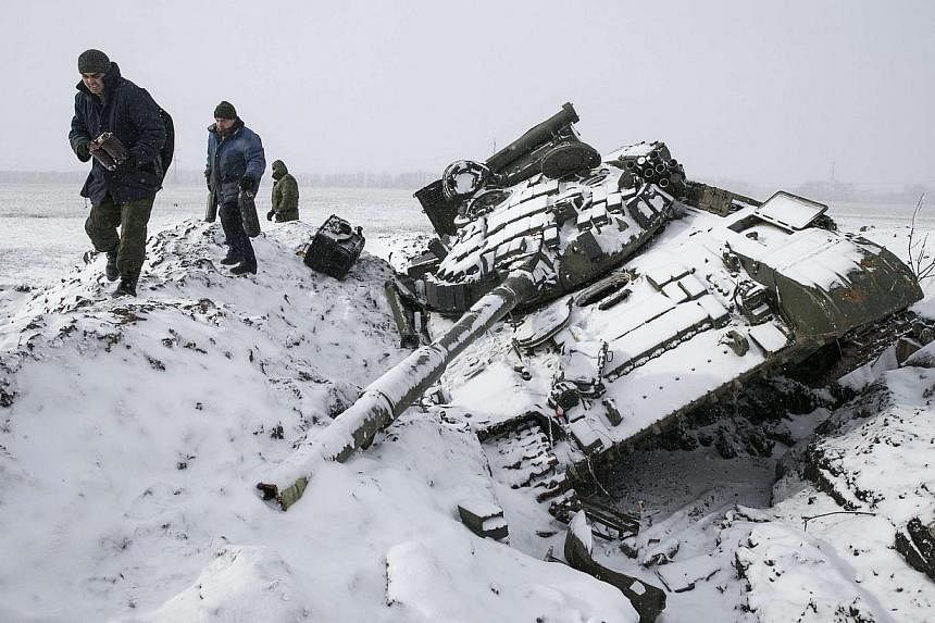 Members of the separatist self-proclaimed Donetsk People's Republic army collect parts of a destroyed Ukrainian army tank in the town of Vuhlehirsk, about 10 km (6 miles) to the west of Debaltseve, on Feb 16, 2015.&nbsp;Ukraine troops and pro-Russian