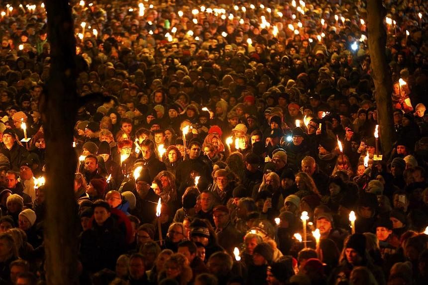 People hold candles during a memorial march on Monday for those killed on Saturday by a 22-year-old gunman in Copenhagen. -- PHOTO: REUTERS