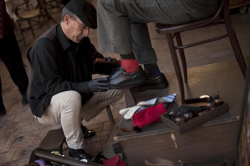 Spanish shoeshiner Javier Castano (left) shines shoes on Monday in Malaga. -- PHOTO: AFP&nbsp;