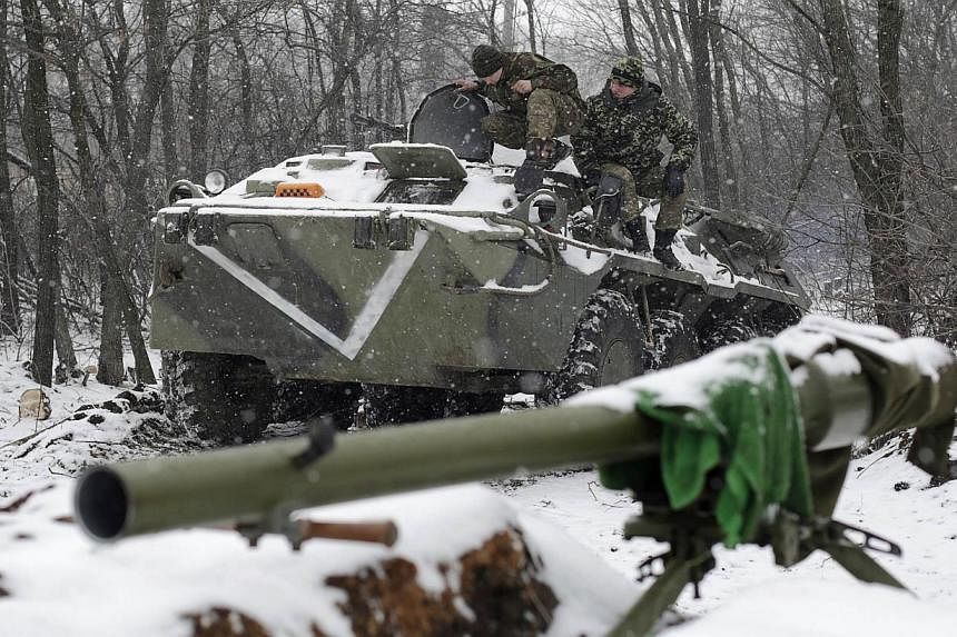 Ukrainian servicemen sit on an Armoured Personnel Carrier (APC) at a checkpoint near the town of Svitlodarsk, Donetsk region, on Monday. A two-day-old truce in Ukraine is under threat with fighting raging around a strategic railway hub, putting in pe