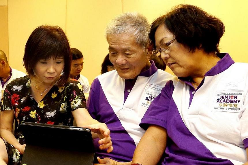 Senior Minister of State, Ministry of Health and Ministry of Manpower, Dr Amy Khor Lean Suan (left) showing Yong Poo Siyong (centre) and Koh Wei Choo, how to use Facebook on the iPad. -- ST PHOTO: CHEW SENG KIM&nbsp;
