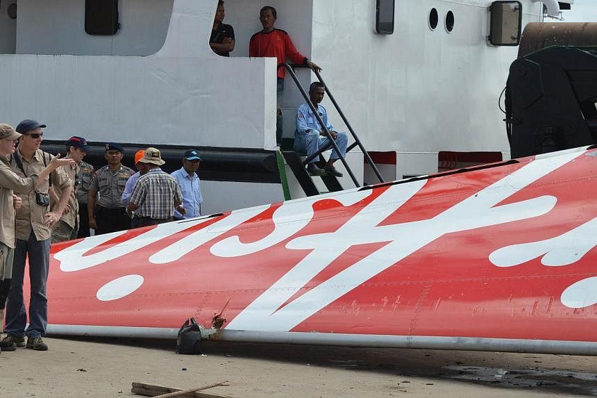 Foreign investigators (left) examining the tail of the AirAsia flight QZ8501 in Kumai on Jan 12, 2015, after debris from the crash was retrieved from the Java Sea. Indonesia will release the final report&nbsp; onlast year's AirAsia plane crash by Aug
