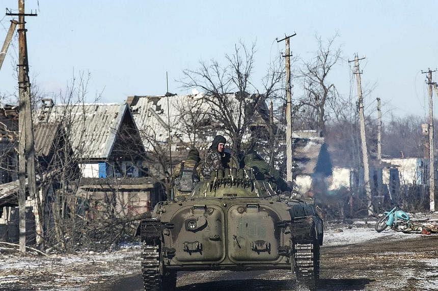 Fighters with separatist self-proclaimed Donetsk People's Republic army ride atop a moving armoured personnel carrier in the village of Nikishine, south east of Debaltseve on Feb 17, 2015. Pro-government forces began on Wednesday to pull out of the t