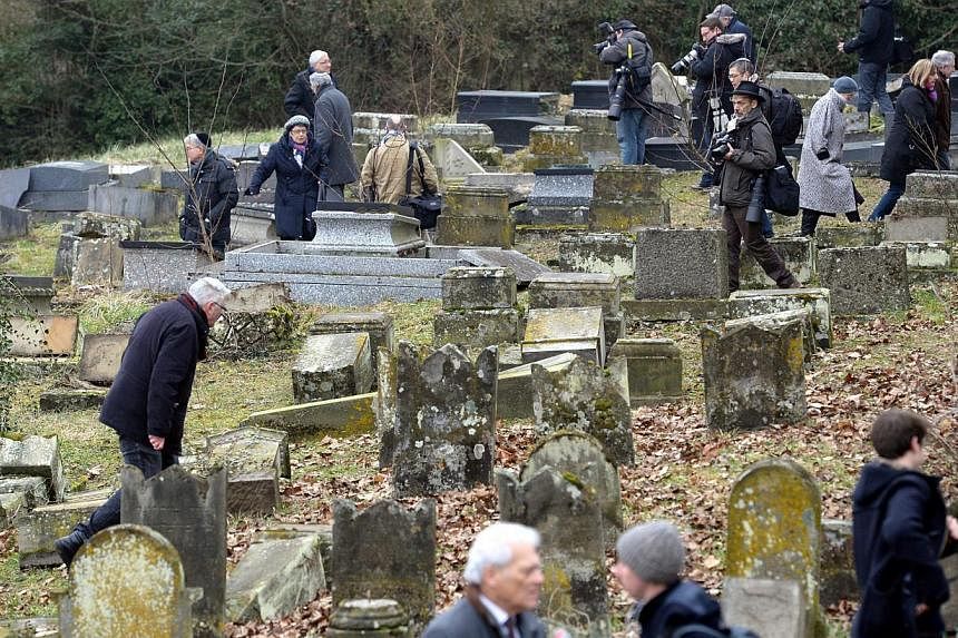 People eye the Jewish cemetery on which hundreds of Jewish graves were desecrated in Sarre-Union, France, on Feb 17, 2015. -- PHOTO: EPA