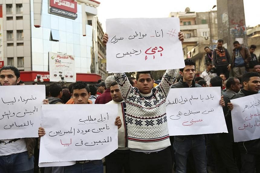 Egyptian Christians hold placards during a protest against the killing of Egyptian Coptic Christians by militants in Libya associated with the Islamic State in Iraq and Syria (ISIS), in Cairo on Feb 16, 2015. -- PHOTO: REUTERS&nbsp;