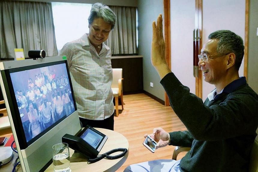Prime Minister Lee Hsien Loong, accompanied by his wife Ho Ching, greeting his ministerial colleagues via a video-link to the Cabinet room at the Istana yesterday. Mr Lee will spend the Chinese New Year break recuperating from prostate cancer surgery