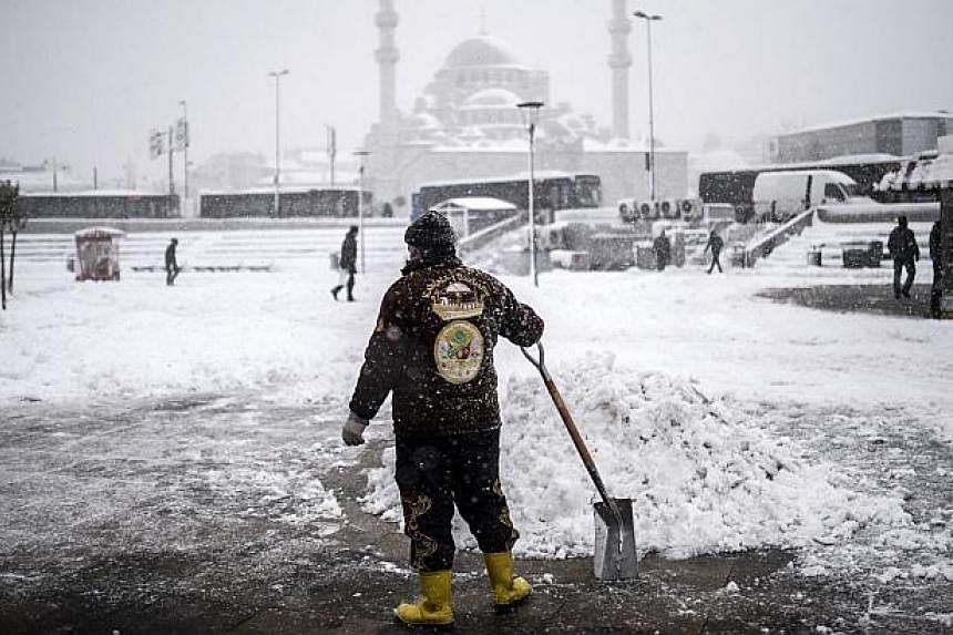 A man holds a shovel as he tries to clear a street during heavy snowfall in the European side of Istanbul on Feb 18, 2015. -- PHOTO: AFP