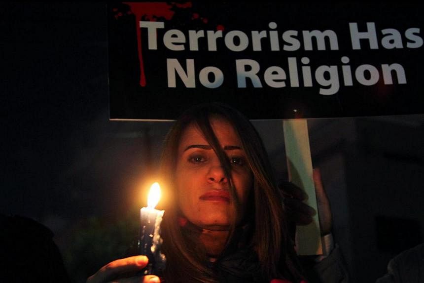 A Jordanian woman holds a candle during a gathering in front of the Egyptian embassy in Amman, Jordan on Tuesday. People gathered there to light candles and prayed to show solidarity with Egypt after the killing of 21 Egyptian workers by ISIS militan