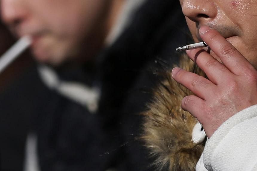 People smoke in a designated smoking area in Tokyo, Japan, early this month. -- PHOTO:&nbsp;BLOOMBERG