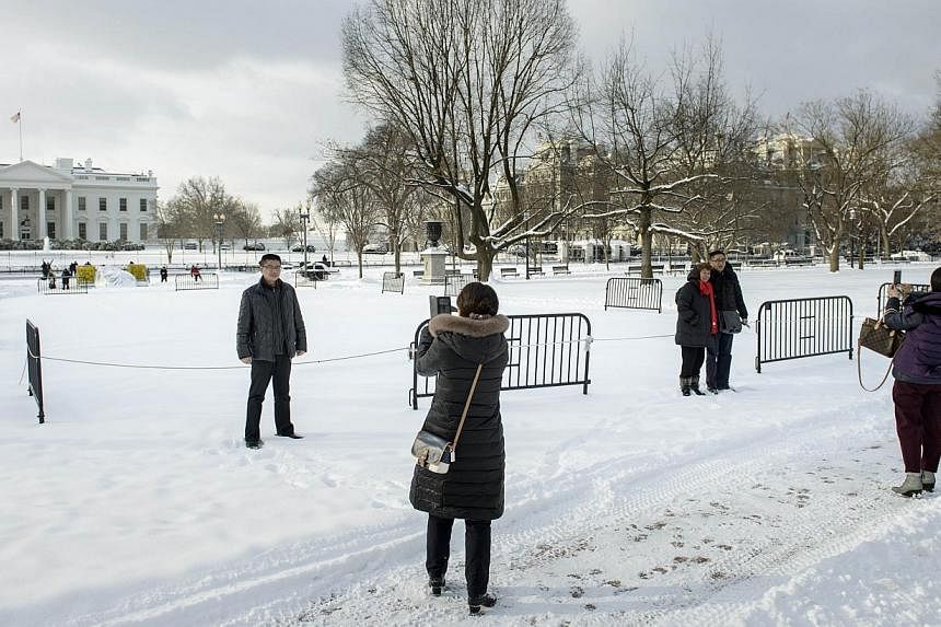 People pose for photos in the snow in Lafayette Square near the White House on Tuesday in Washington, DC. The DC area received several inches of snow effecting public transportation and shutting down the Federal Government. -- PHOTO: AFP