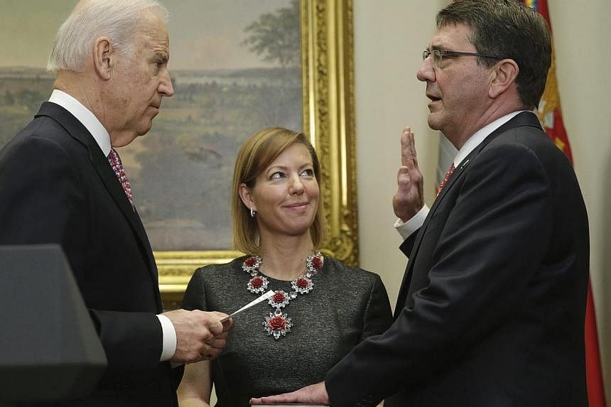 United States Vice-President Joe Biden (left) swears in Ashton Carter (right) as the new US Secretary of Defence in Washington Feb 17, 2015. Carter's wife Stephanie (centre) holds the Bible. Carter served as the deputy defence secretary, the departme