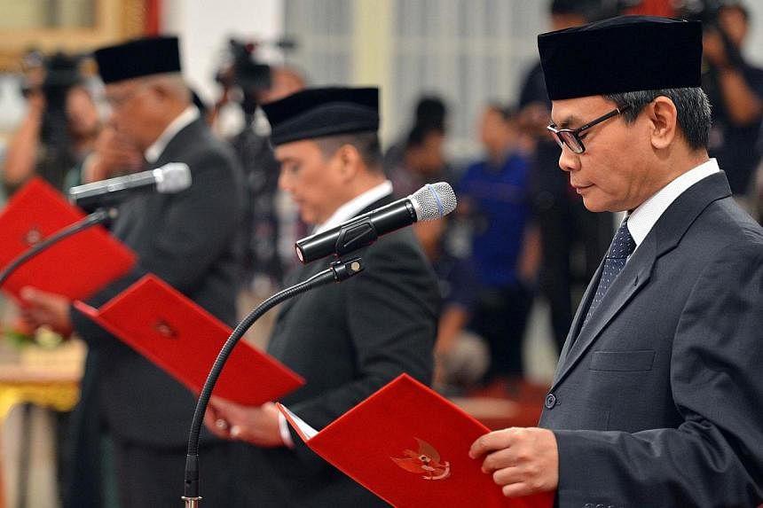 (From right) Johan Budi, Indriyanto Seno Aji and Taufiequrahman Ruki taking their oath before President Joko Widodo (not seen) during a ceremony at the presidential palace in Jakarta on Feb 20, 2015. -- PHOTO: AFP&nbsp;