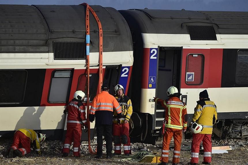 Firefighters inspect the site of a train crash at the train station of Rafz, northern Switzerland, on Feb 20, 2015. Two trains slammed into each other north of Zurich early on Friday, leaving passengers injured, Swiss police said.&nbsp;-- PHOTO: AFP