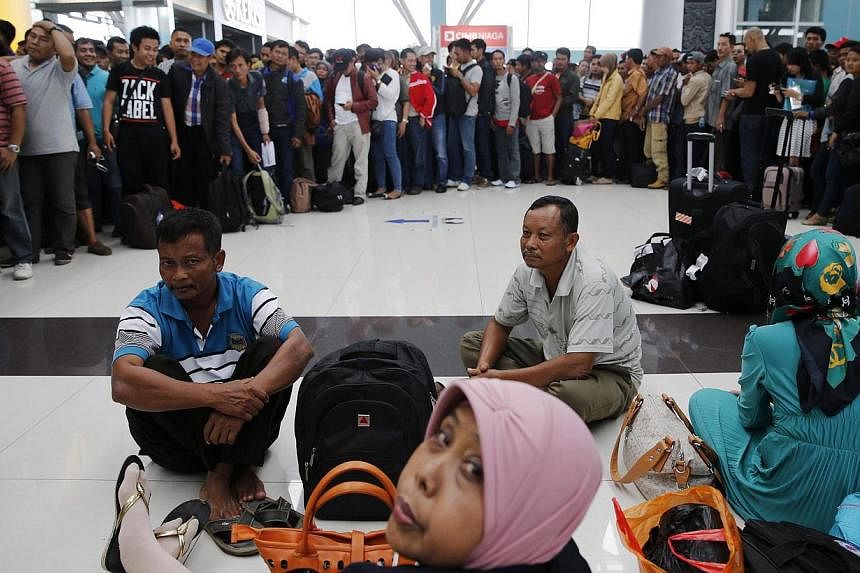 Lion Air passengers stand in a line to claim their tickets money back after their flights were delayed at Soekarno-Hatta airport in Jakarta on Feb 20, 2015. -- PHOTO: REUTERS