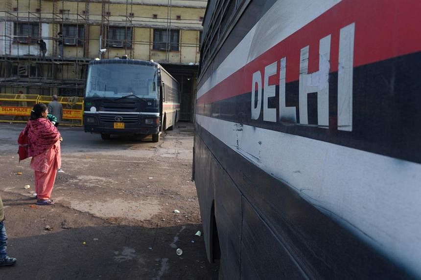 Indian residents walk past police buses used to ferry inmates from jail to court outside the Tis Hazari District court in New Delhi on Jan 15, 2015.&nbsp;Police in Delhi arrested four men on Friday in connection with the alleged gang-rape of a Nigeri