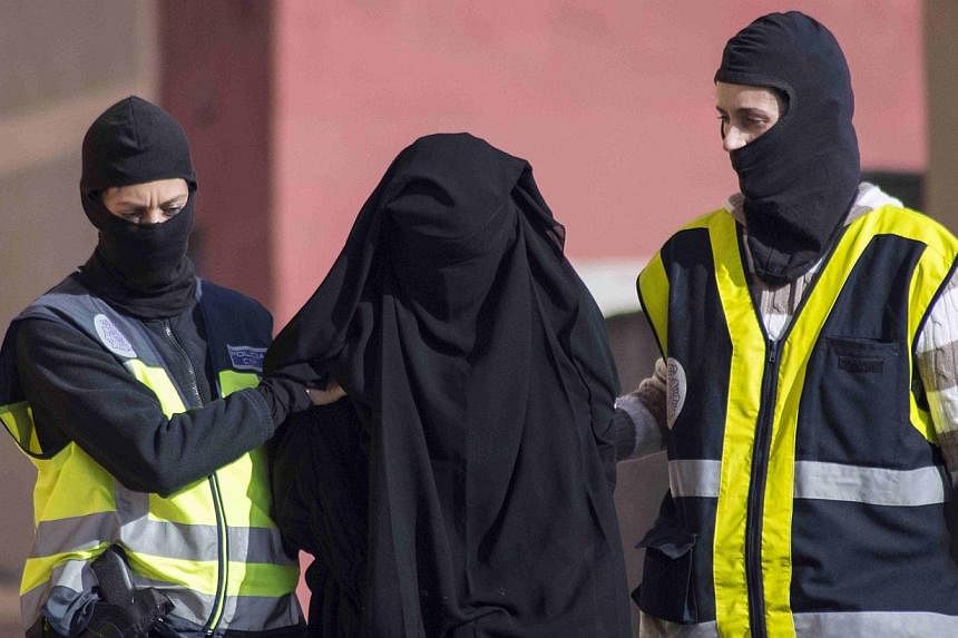 Masked Spanish police officers lead a detained woman in Melilla on Dec 16, 2014.&nbsp;Spain said on Tuesday it had broken up an online network accused of recruiting young women to join the Islamic State in Iraq and Syria (ISIS) and arrested four susp
