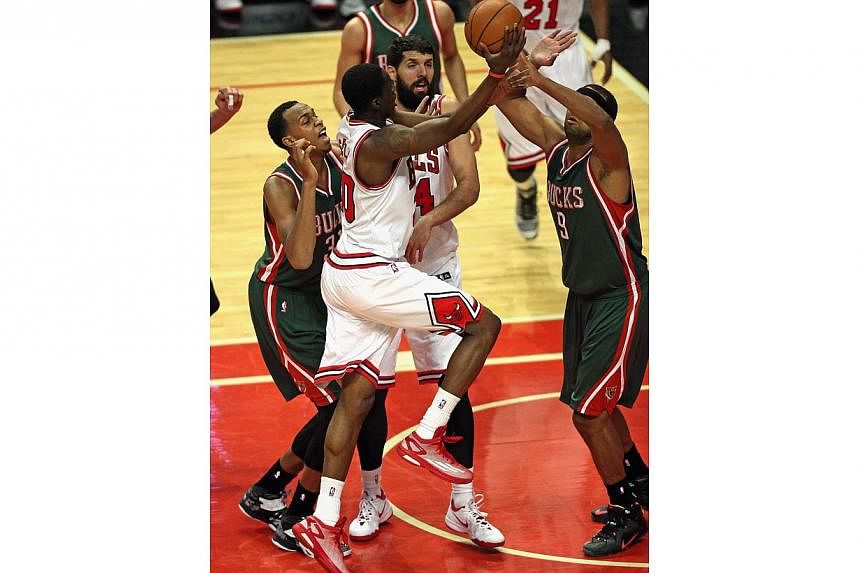 Tony Snell (centre) of the Chicago Bulls drives to the basket between John Henson (left) and Jared Dudley (right) of the Milwaukee Bucks on his way to a game-high 20 points at the United Center on Feb 23, 2015 in Chicago, Illinois. -- PHOTO: AFP