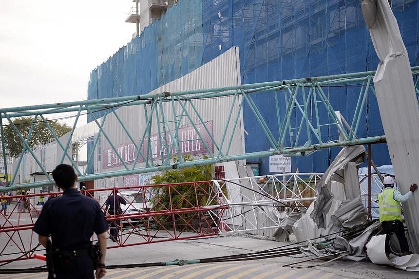 A crane from the construction site of upcoming condo Sant Ritz, in Potong Pasir, toppled over on Tuesday and crashed into the front yard of a semi-detached house across the road. -- ST PHOTO: MARK CHEONG